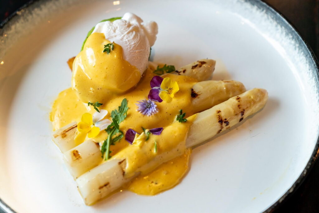 elingea-recipe-Gourmet grilled white asparagus with poached egg serve with hollandaise savory sauce decorate with edible colorful flowers